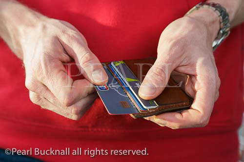 A man removing a credit card from a wallet to pay 
for a purchase. England, UK, Britain, Europe. MR 
14/32