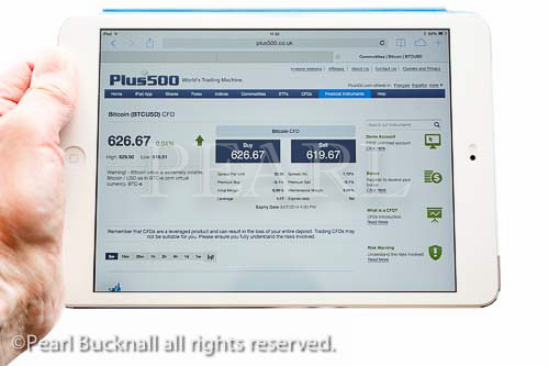 Person holding an iPad mini tablet whilst looking at 
Plus500 website quoting Bitcoin exchange rate and 
trading prices in USD isolated on white background. 
MR 14/04
