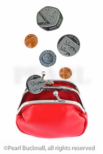 Sterling coins dropping into a red money purse open. 
Studio, still life, UK, Britain