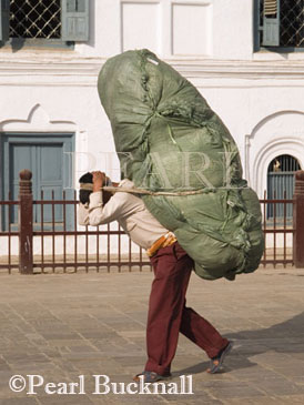 PORTER CARRYING LOAD SHERPA STYLE past part of 
Old Palace complex in Basantapur Square. Kathmandu 
Nepal Asia
