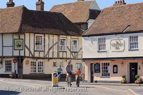 People cycling past 15th century Admiral Owen pub 
and 16th century Crispin Inn in historic town of 
Sandwich, Kent, England, UK, Britain