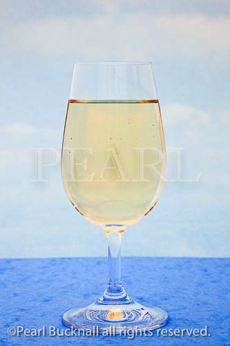 Glass of white wine with a blue sky background. Studio 
still life. 