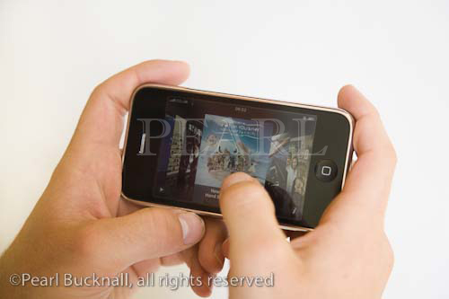 Man's hand holding Apple iphone mobile phone 
viewing itunes albums. UK Britain Europe

