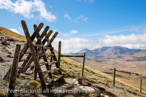 Two stiles on path from Moel Siabod to Capel Curig 
with view to Mount Snowdon Horseshoe in mountains 
of Snowdonia National Park. Capel Curig, Conwy, 
North Wales, UK, Britain.