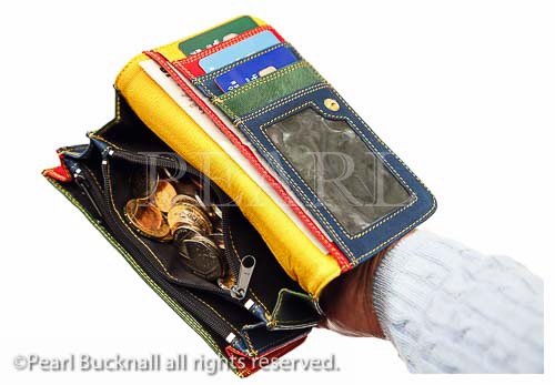 A person's hand holding a purse open with money 
sterling coins on a white background. England, UK, 
Britain, Europe.