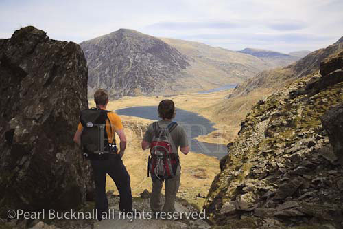 Cwm Idwal, North Wales, UK. Walkers looking down to 
Llyn Idwal lake from the Devil's Kitchen in the 
mountains of Snowdonia National Park.  

Keywords: hiking hike mountain walk men hikers 
