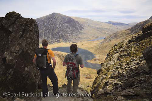 Cwm Idwal, North Wales, UK. Walkers looking down to 
Llyn Idwal lake from the Devil's Kitchen in the 
mountains of Snowdonia National Park.  

Keywords: hiking hike mountain walk men hikers 