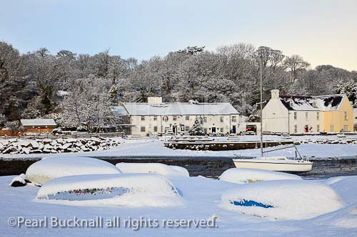 Snow scene with upturned boats on the coast in 
winter. Red Wharf Bay (Traeth Coch), Isle of 
Anglesey, North Wales, UK, Europe
