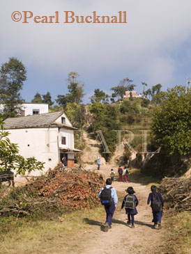 CHILDREN WALKING to SCHOOL on dirt road from 
Kavre village to Dhulikhel near the Kali Temple on the 
hill in the Himalayan foothills of rural Nepal Dhulikhel, 
Kathmandu Valley, Nepal, Asia
