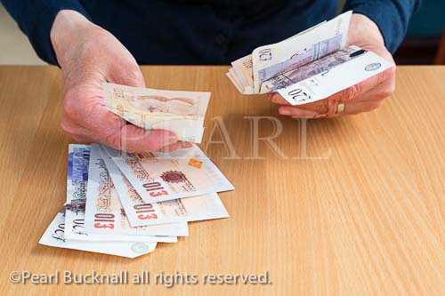 A senior person counts money in ten and twenty 
pound notes to pay for something over a counter. 
England, UK, Britain, Europe. MR 15/13