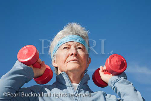 Senior woman exercising with dumbbell hand weights 
outdoors. UK Britain Europe. 