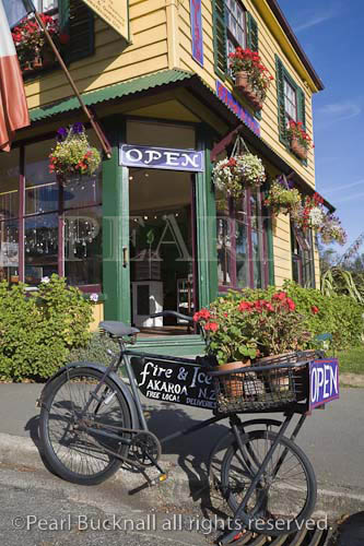 Akaroa, South Island, New Zealand, Open sign on old 
bicycle outside shop door in colourful yellow painted 
wooden clapboard building
