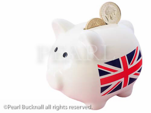 Piggy bank with British Union Jack and two sterling 
pound coins in the slot isolated on a white 
background. UK, Britain, Europe