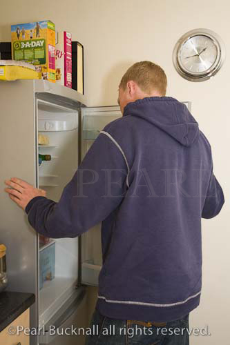 Man looking in a refrigerator with open door in 
kitchen at lunch time. England Britain UK Europe

person fridge caucasian house indoors