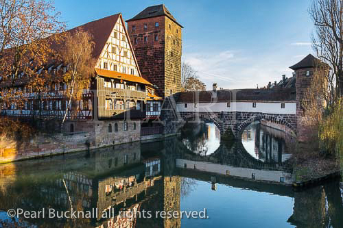 15th century Weinstadle timbered building and 
Henkersteg or Hangman's Bridge reflected in Pegnitz 
River.  Nuremberg, Bavaria, Germany