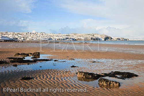 View along empty sandy beach to snow on the 
headland at low tide in winter. Benllech, Isle of 
Anglesey, North Wales, UK, Europe. 

Keywords: coast scene Britain British Welsh Ynys Mon