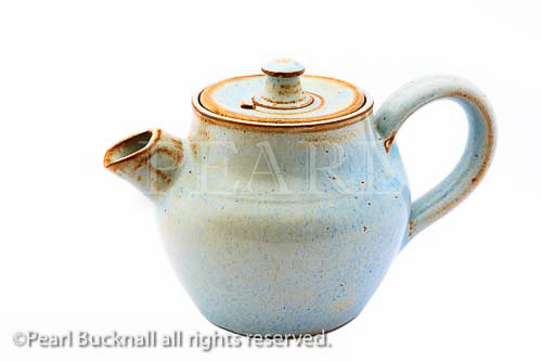 Small ceramic pottery teapot isolated on a white 
background