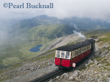 SNOWDON RAILWAY STEAM TRAIN approaching 
Summit Station with view west towards Nant-y-Betws 
through swirling cloud. Llanberris, Gwynedd, North 
Wales, UK, Europe

