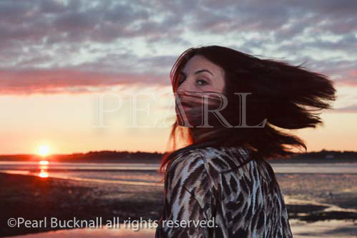 Portrait of a young woman swishing her hair at the 
coast with the sunset over the Menai Strait as 
backdrop. Caernarfon, Gwynedd, North Wales, UK, 
Britain