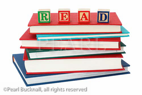 Stack of generic hardback books with the word 
READ spelt with letter blocks on top to illustrate a 
reading concept. England UK Europe
