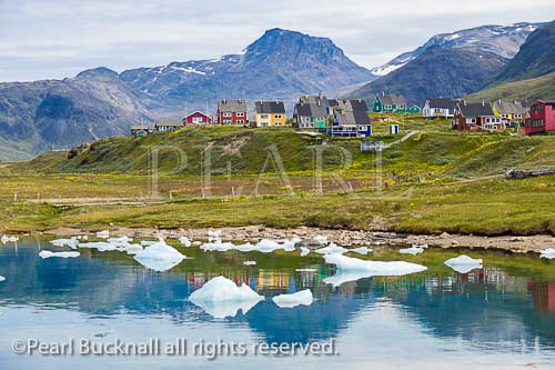 Typical traditional painted wooden houses from across 
an inlet with small icebergs. Qajaq Harbour, Narsaq, 
Kujalleq, South Greenland