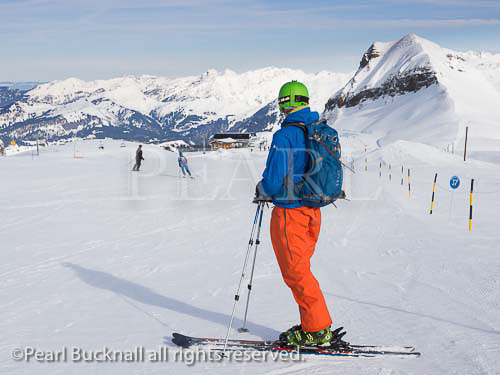 Skier skiing blue run Serpentine on Les Grandes 
Platieres in Le Grand Massif ski area with views of 
snowcapped mountains in French Alps. Flaine, Haute 
Savoie, Rhone-Alpes, France, Europe. 