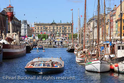 Tourists on canal tour boat with old wooden boats 
moored in Nyhavn, Copenhagen, Zealand, Denmark, 
Europe