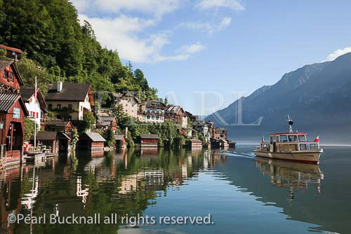 Tourists lake cruise boat on Hallstattersee approaching 
the World Heritage lakeside town in the Austrian Alps. 
Hallstatt, Salzkammergut, Austria, Europe. 