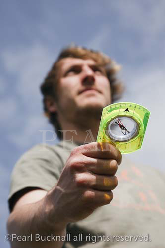 Young man navigating with a compass to find the 
direction Britain, UK, Britain. 
