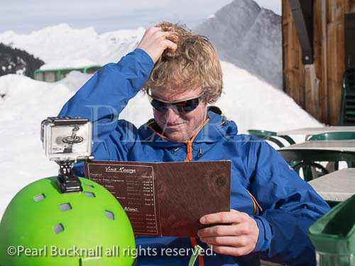 Man scratching his head whilst trying to decide what to 
eat from a menu in Gite du Lac de Gers ski restaurant. 
Sixt, Samoens, Haute Savoie, Rhone-Alpes, France, 
Europe. 