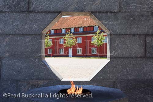 Eternal flame with barracks seen through octagonal 
window in granite wall in Danish National Monument 
of Remembrance, Princess Bastion in Kastellet or 
Frederikshavn Citadel Copenhagen, Zealand, Denmark, 
Scandinavia, Europe