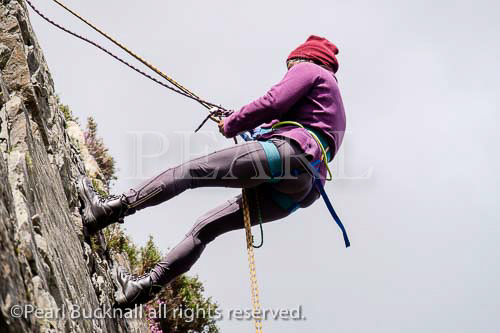 Female rock climber abseiling with safety rope on a 
rockface. Snowdonia, North Wales, UK, Britain, 
Europe