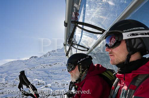 Two skiers on the Valfagehr chairlift in the Austrian 
Alps in winter. St Anton am Arlberg, Tyrol, Austria, 
Europe.