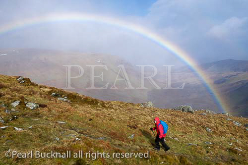 Hiker hiking in wet weather with a rainbow on Pen yr 
Helgi Du in the Carneddau mountains of Snowdonia 
National Park, North Wales, UK, Britain