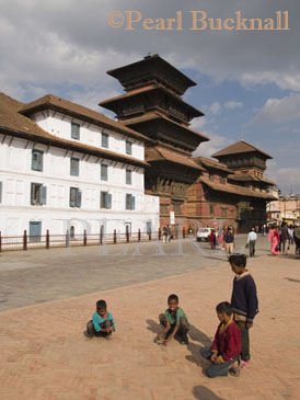 BASANTAPUR SQUARE with people strolling and young 
boys playing marbles in front of Old Palace complex 
and nine storey Basantapur Tower 1768. Kathmandu 
Nepal Asia
