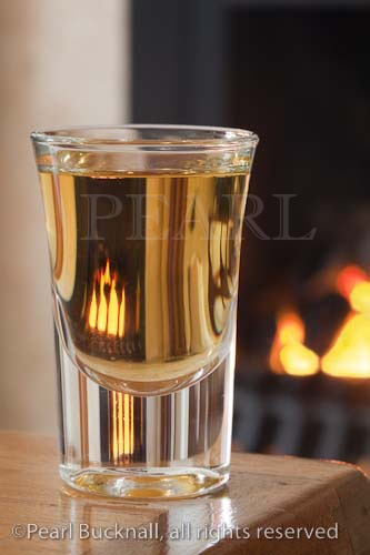 Dram of whiskey in a glass on a table by an open coal 
fire

Keywords: still life alcohol homely fireplace warm 
room 