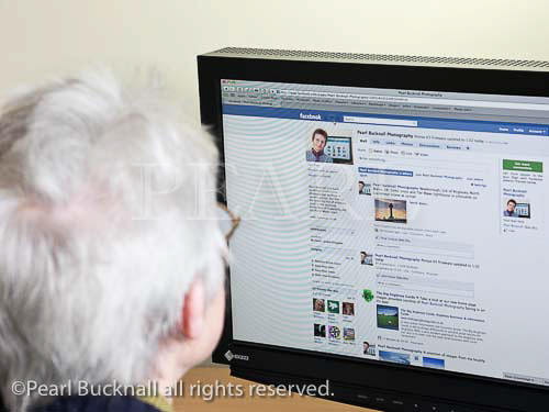 Senior woman looking at a Facebook page on the 
website. UK, Britain, Europe. 