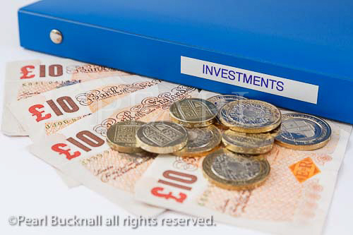 Investments folder with sterling ten pound notes and 
coins. Investing money concept. UK, Britain