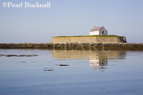 Historic 12th century Llangwyfan church on small 
island reflected in sea at Porth Cwyfan Aberffraw 
Anglesey North Wales UK 

Keywords: beach coast CADW landscape landmark 
nobody scenic sea water

