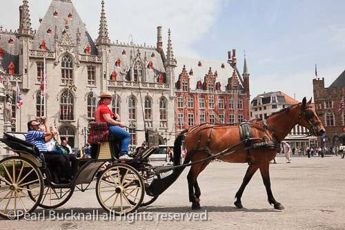 Horse and carriage tourists sightseeing tour in the 
historic square of Markt, Bruges, Belgium, Europe. 