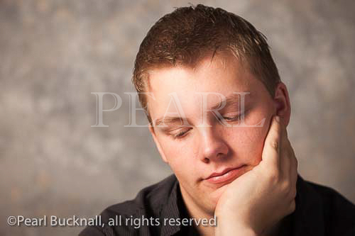Portrait of a young man with a pensive expression 
resting chin on his hand. UK, Britain