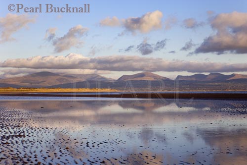 Tidal pool reflecting clouds on mountains of 
Snowdonia on Traeth Llanddwyn conservation beach  
Newborough Anglesey North Wales UK 

Keywords: beach coast landscape nobody scenic sea 
water