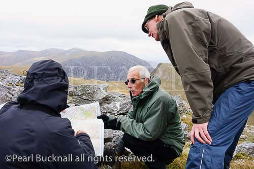Three Ramblers reading an Ordnance Survey map on a 
walk up Elidir Fawr in mountains of Snowdonia 
National Park, Gwynedd, North Wales, UK, Britain, 
Europe.