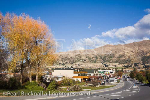 View along main street of lakeside resort town in 
autumn with southern mountains beyond. Wanaka 
Otago South Island New Zealand