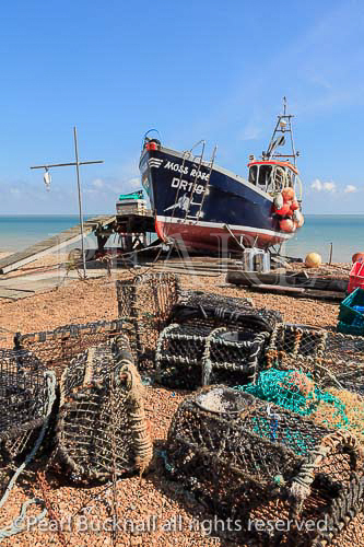Fishing boat and lobster pots on the south coast 
shingle beach in Deal, Kent, England, UK, Britain
