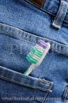A toothbrush in the back pocket of a pair of blue 
denim jeans