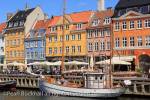 Old wooden boats moored on canal by pedestrianised 
waterfront street with outdoor cafes and colourful 
buildings in Nyhavn, Copenhagen, Zealand, Denmark, 
Europe