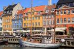 Old wooden boats moored on canal by pedestrianised 
waterfront street with outdoor cafes and colourful 
buildings in Nyhavn, Copenhagen, Zealand, Denmark, 
Europe