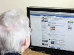 Senior woman looking at a Facebook page on the 
website. UK, Britain, Europe. 