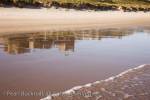 Bamburgh Castle reflected in wet sand on empty 
beach. Bamburgh, Northumberland, England, UK, 
Europe.

Keywords: British landmark English coast reflections 
sea
